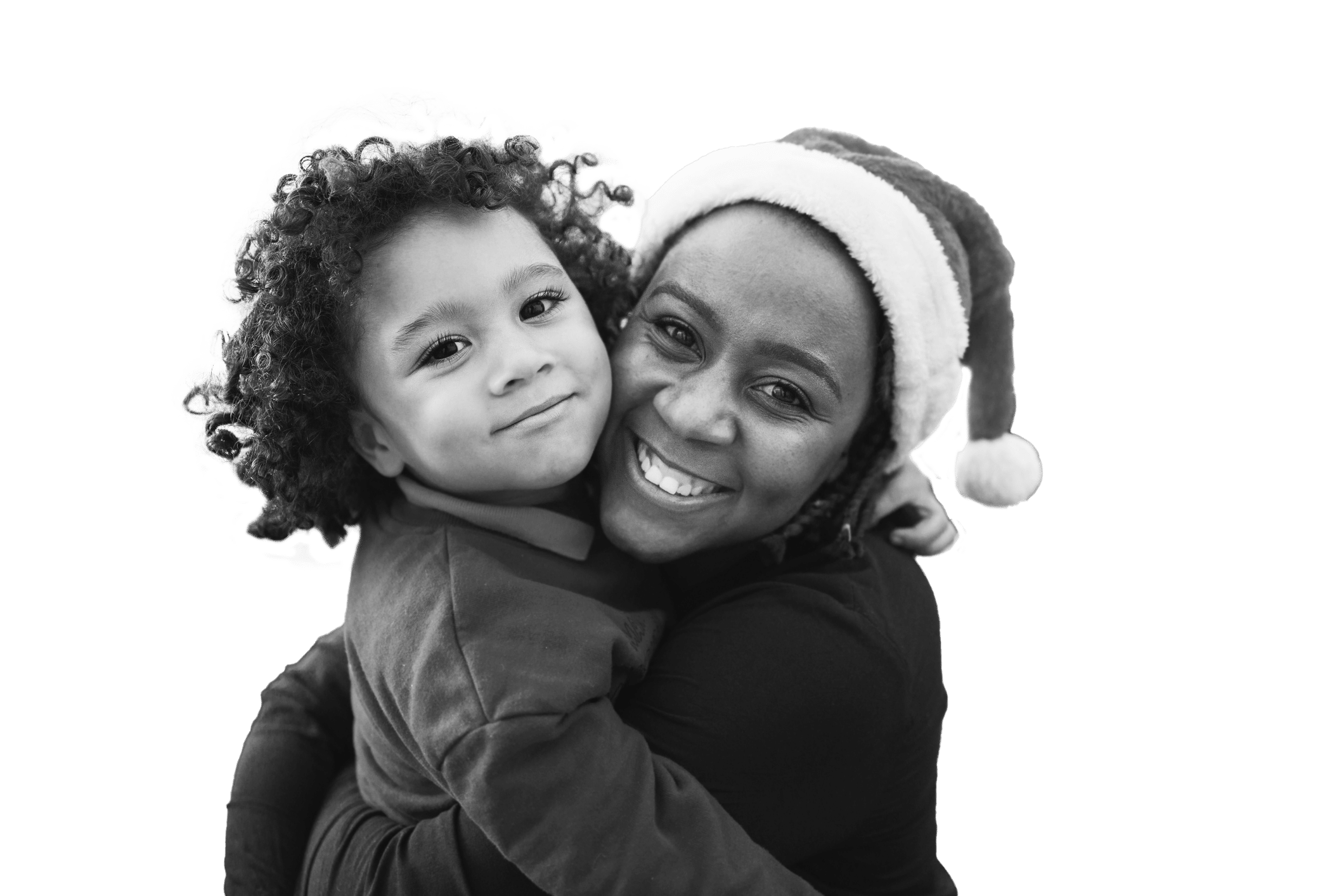 A smiling woman wearing a Santa hat hugs a young child with curly hair. Both are looking at the camera and appear happy, conveying a joyful moment. The image is in black and white.
