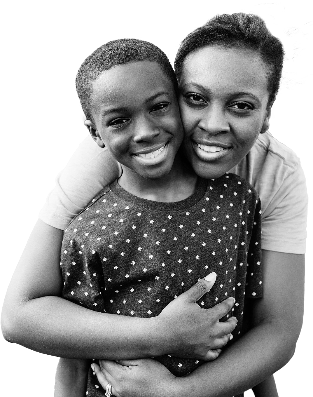 A woman hugs a smiling young boy from behind. They are both looking at the camera, close together, and appear happy. The image is in black and white with a white background.