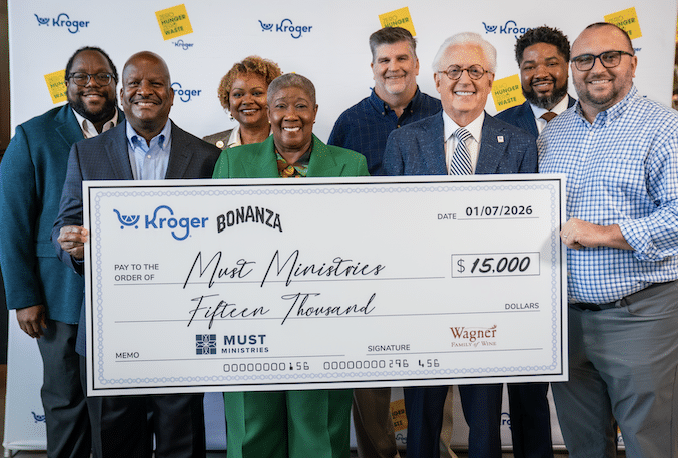 A group of people smiling and holding a large ceremonial check for $15,000 made out to Must Ministries from Kroger and Wagner, supporting efforts to help the food insecure, with a Kroger Bonanza banner in the background.