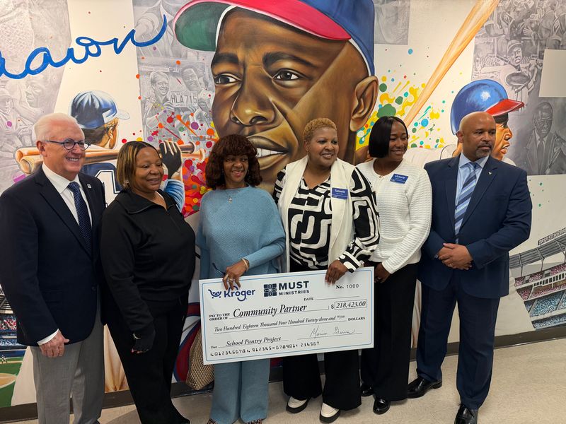 Six people stand smiling in front of a Hank Aaron mural, holding a large ceremonial check from Kroger to MUST Ministries for $278,142. They appear to be at a check presentation or charity event.